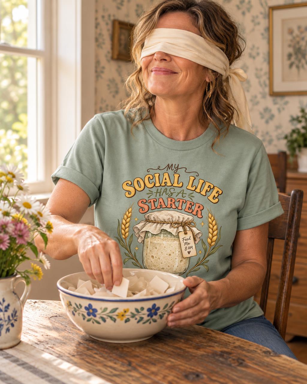 Woman wearing a Knead More Fun T-shirt while drawing a name from a mixing bowl